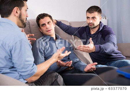 Three anxious men discussing on sofa Three anxious men discussing on sofa 63377070