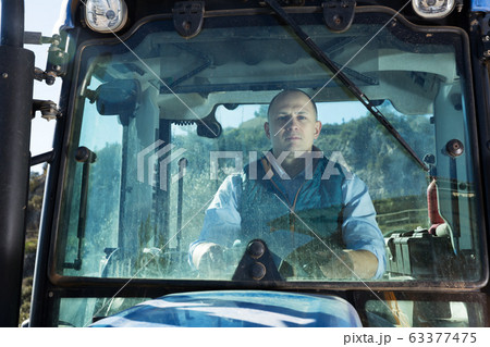 Man sitting in tractor cab 63377475