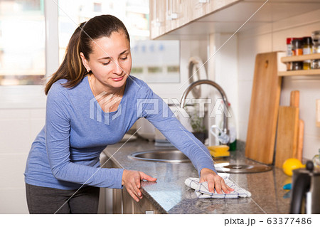 Smiling woman is cleaning surface on the kitchen at the home Smiling woman is cleaning surface on the kitchen at the home 63377486