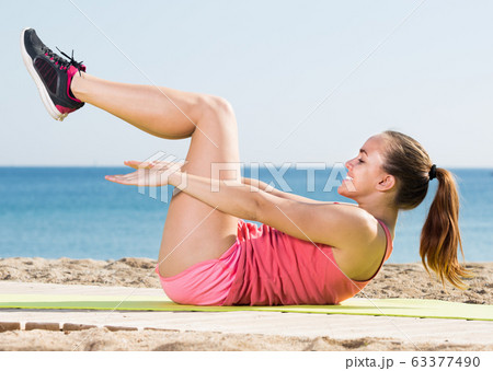 Smiling sportswoman training at sea beach Smiling sportswoman training at sea beach 63377490