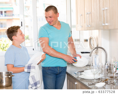 Smiling bou is washing dishes with his father together Smiling bou is washing dishes with his father together 63377528