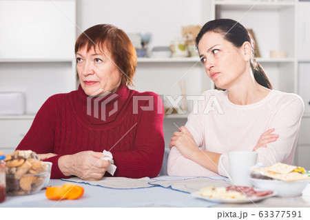 Unhappy adult female quarrel with daughter at table 63377591