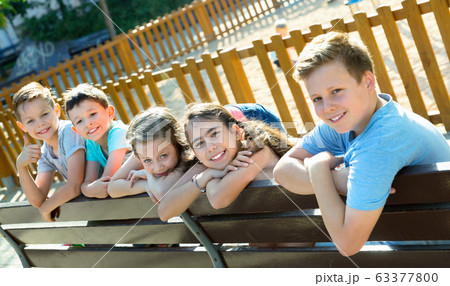 Five children sitting on a bench at the playground 63377800