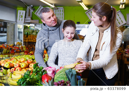 Happy family with daughter buying ripe bananas Happy family with daughter buying ripe bananas 63378099
