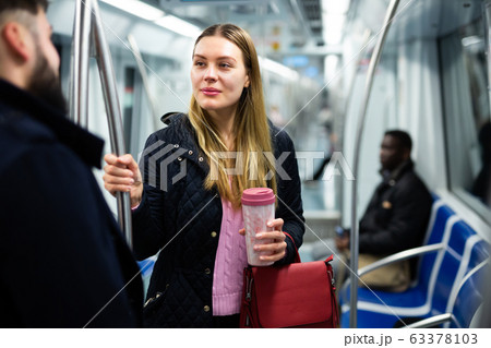 Woman chatting with fellow traveler in subway car 63378103