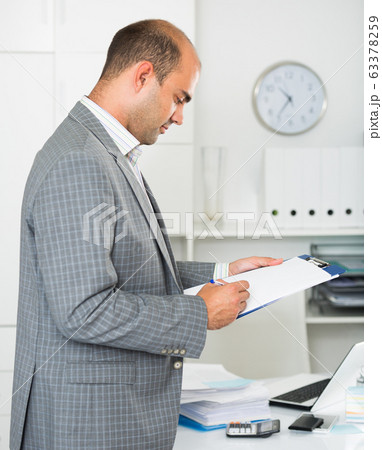 Man working in the office at the laptop with documents 63378259