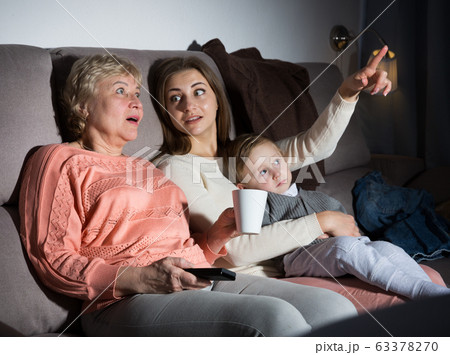 Woman with her mother and son are watching film in time evening rest 63378270