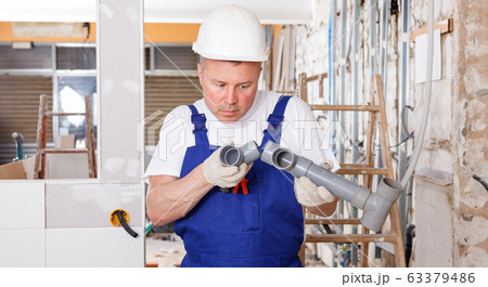 Plumber assembling plastic pipes 63379486