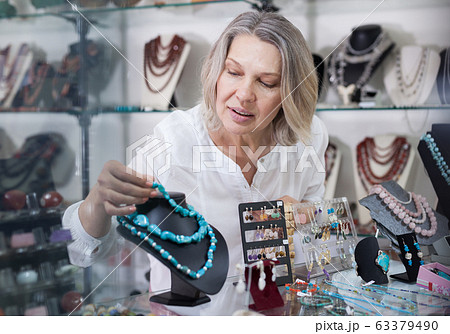 Woman jewelry store seller puts necklaces and earrings on the counter 63379490