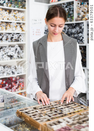Seamstress looking for buttons in shop 63379501