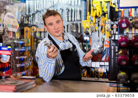 Positive seller standing in hardware shop 63379658