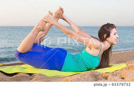 Woman in blue T-shirt is practicing stretching Woman in blue T-shirt is practicing stretching 63379732
