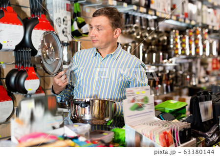 Man chooses saucepan in store of household appliances 63380144