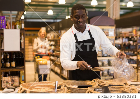 Man working in bulk food department of supermarket Man working in bulk food department of supermarket 63380331