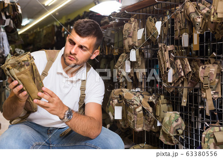 guy looking holster for pneumatic weapon in army store 63380556