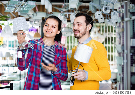 Smiling man and girl in lighter shop discussing purchase of night light 63380783