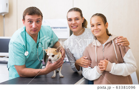 Cheerful mother and daughter visiting veterinarian clinic with their puppy Cheerful mother and daughter visiting veterinarian clinic with their puppy 63381096