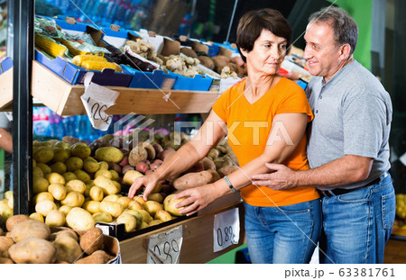 Smiling couple is choosing potato in the supermarket. 63381761