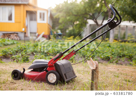 Grass mower stands on green lawn in summer garden Grass mower stands on green lawn in summer garden 63381780