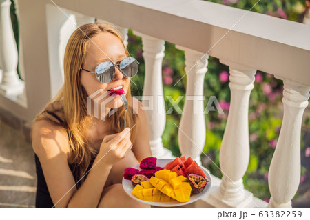 Young woman resting on a balcony with a plate of fruit. life-work balance, relaxation healthy 63382259