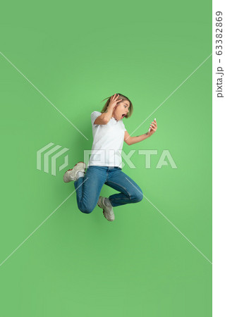 Caucasian young woman's portrait on green studio background 63382869