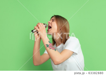 Caucasian young woman's portrait on green studio background 63382880