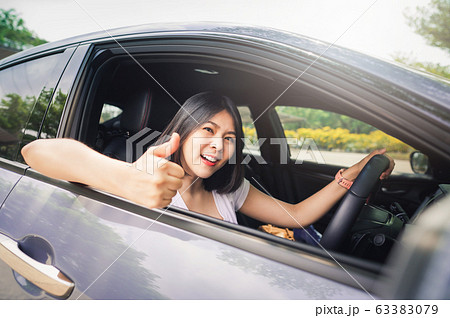 woman driving her new car and showing thumb up 63383079