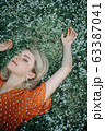 Beautiful lying woman enjoying daisy field, pretty girl relaxing outdoor. Close-up 63387041