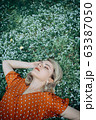 Beautiful lying woman enjoying daisy field, pretty girl relaxing outdoor. Close-up 63387050