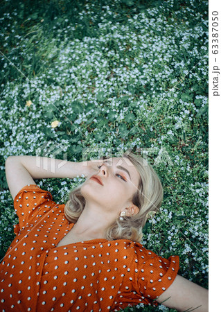 Beautiful lying woman enjoying daisy field, pretty girl relaxing outdoor. Close-up 63387050