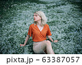Beautiful woman enjoying daisy field, pretty girl relaxing outdoor 63387057