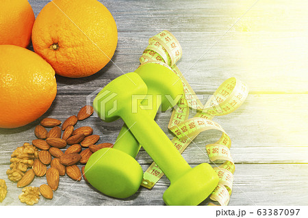 Lots of oranges, dumbbells, measuring tape on a 63387097