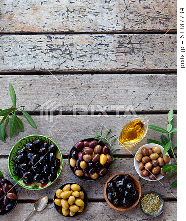 Assortment of fresh olives on a plate with olive tree brunches. Wooden background. Copy space. Top view. 63387734