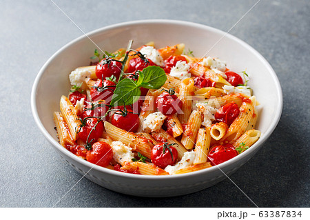 Pasta penne with roasted tomato, sauce, mozzarella cheese. Grey background. Close up. Pasta penne with roasted tomato, sauce, mozzarella cheese. Grey background. Close up. 63387834