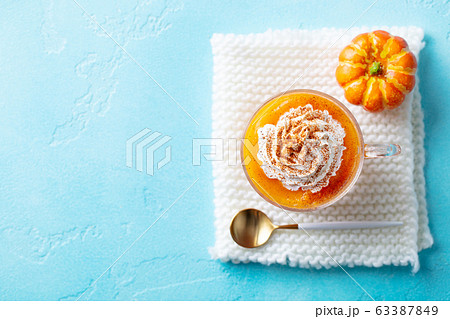 Pumpkin latte in glass cup. Blue background. Copy space. Top view. Pumpkin latte in glass cup. Blue background. Copy space. Top view. 63387849