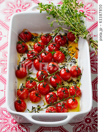 Roasted cherry tomatoes with herbs in baking dish. Close up. Roasted cherry tomatoes with herbs in baking dish. Close up. 63387850