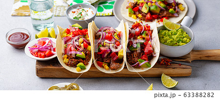 Taco with meat and vegetables on cutting board. Grey background. Close up. Taco with meat and vegetables on cutting board. Grey background. Close up. 63388282