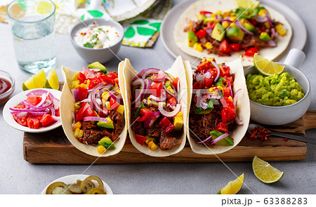 Taco with meat and vegetables on cutting board. Grey background. Close up. Taco with meat and vegetables on cutting board. Grey background. Close up. 63388283