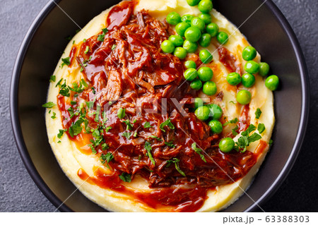 Mashed potatoes with beef meat and green peas in bowl. Grey background. Close up. Mashed potatoes with beef meat and green peas in bowl. Grey background. Close up. 63388303