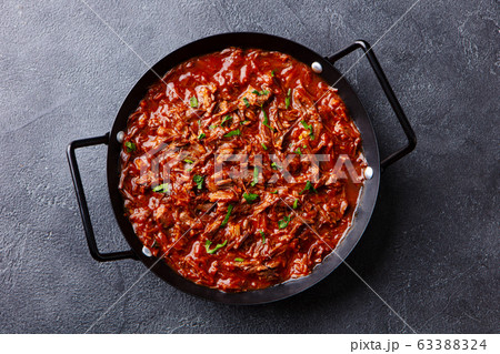 Beef shredded meat with sauce in black pan. Grey background. Close up. Top view. Beef shredded meat with sauce in black pan. Grey background. Close up. Top view. 63388324