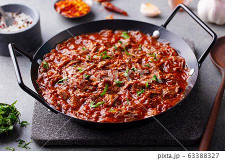 Beef shredded meat with sauce in black pan. Grey background. Close up. Beef shredded meat with sauce in black pan. Grey background. Close up. 63388327