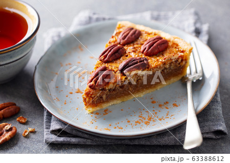 Pecan pie slice on a plate with cup of tea. Grey background. Close up. Pecan pie slice on a plate with cup of tea. Grey background. Close up. 63388612