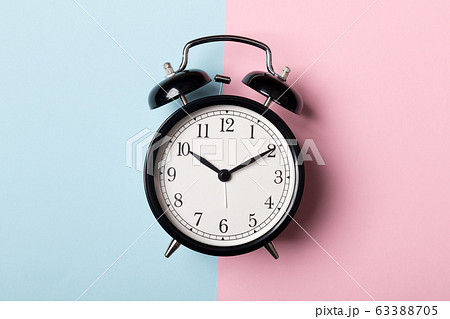 Black vintage alarm clock on blue and pink background 63388705