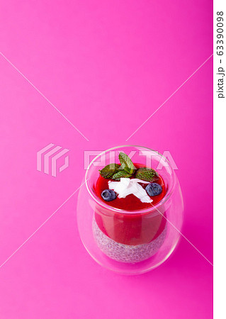 Chia pudding with berry puree in glass on pink background 63390098