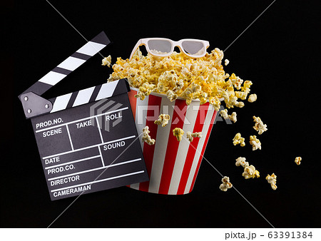 Flying popcorn from striped bucket isolated and 3d glasses on black background Flying popcorn from striped bucket isolated and 3d glasses on black background 63391384