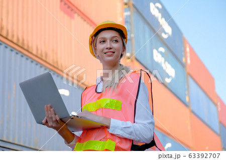 Portrait of beautiful technician use laptop in front of cargo containers with day light 63392707