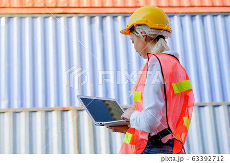 The back of technician woman work with laptop and stand in front of cargo containers The back of technician woman work with laptop and stand in front of cargo containers 63392712