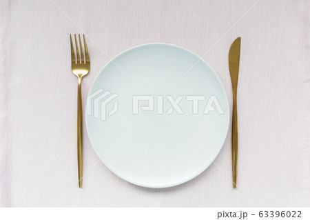 Golden cutlery and plate on pink background 63396022