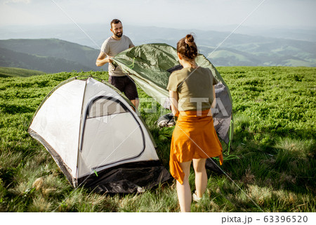 Couple setting up the tent in the mountains 63396520
