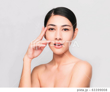 young beautiful asian woman with clean and bright skin, Cosmetic Beauty Concept,hands touch on the cheek, smiling and friendly face isolated on grey background 63399008